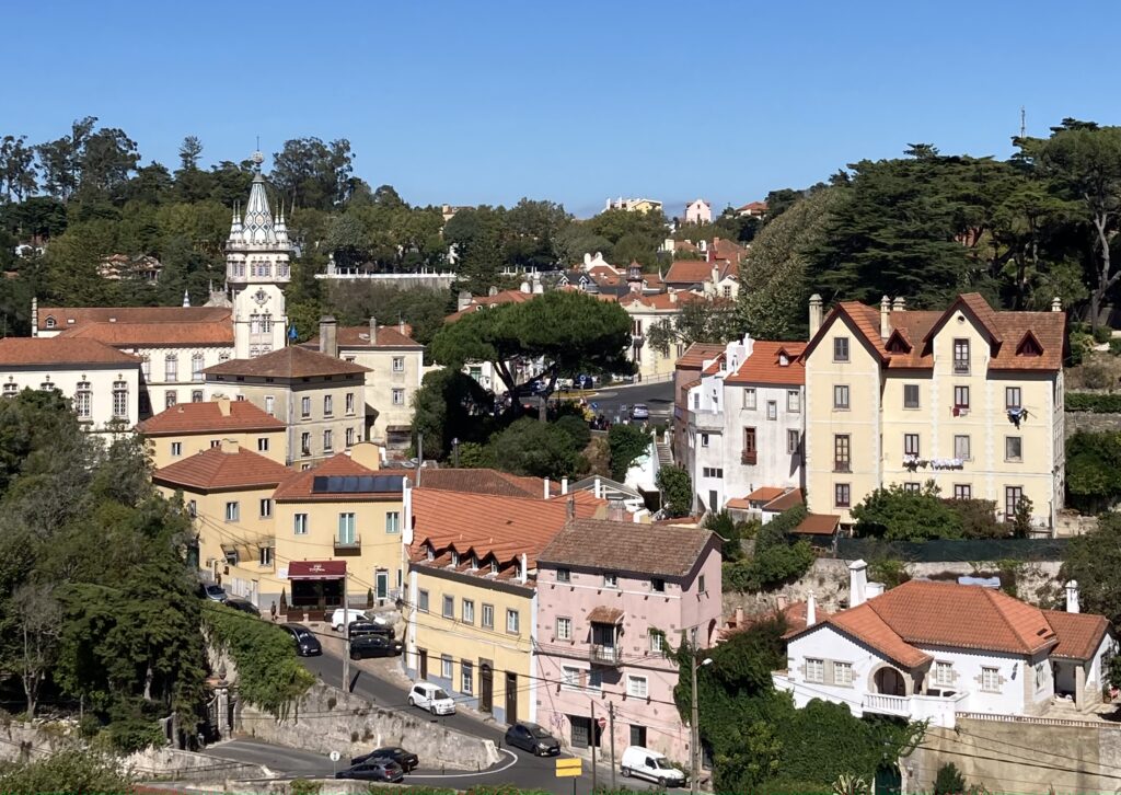 Image of different buildings in Sintra, Portugal. The buildings are colourful and there is a forest in the background.